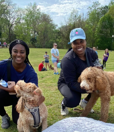 Two smiling women with their dogs in Pelham City Park.