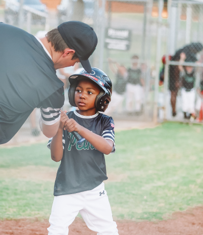 Coach helping boy hold a baseball bat