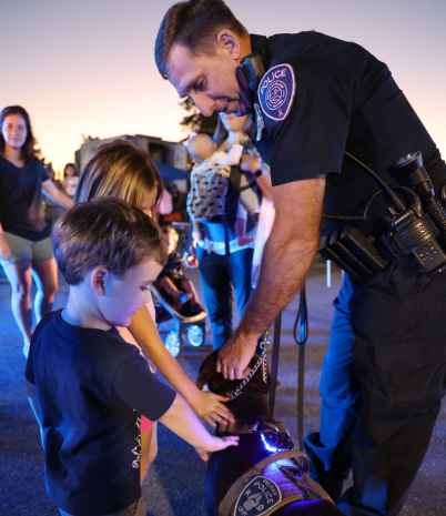 A police officer with a K-9 allows children to pet the dog.