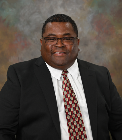 Council Member Markus Hal Snowden is wearing a dark jacket, burgundy printed tie, and white shirt.